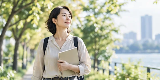 木漏れ日の道を、ノートを持って歩いている人