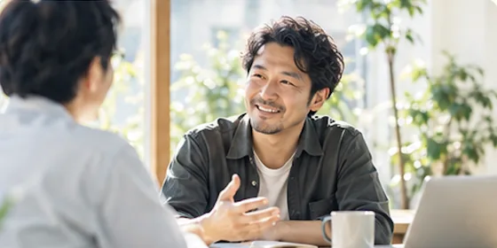 明るい室内で、向かい合って話している二人